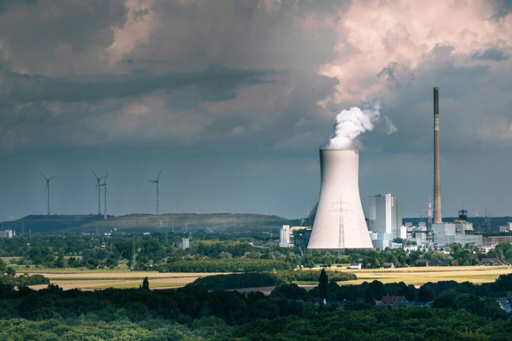 Aerial view of a power plant with steam rising, set against a dramatic sky in Duisburg, Germany.